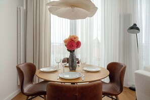 A dining area with a round table, four chairs, a vase with flowers, and a pendant light. - Luxury Apartment with Parking | Air Conditioning | Near the Market Square (Wrocław)