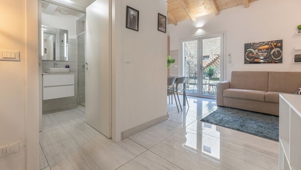 A modern interior with a kitchen, a living area with a sofa, and a dining space. - GuestHost - Bright Apartment with Patio & Parking (Ferrara)