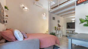 A modern bedroom with a bed, a sofa, a dining table, and a TV. - GuestHost - Bright Apartment with Patio & Parking (Ferrara)