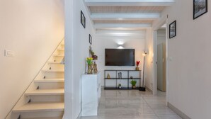 A modern interior with a staircase, a flat-screen TV, and a minimalist decor. - GuestHost - Bright Apartment with Patio & Parking (Ferrara)