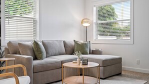 Una sala de estar moderna con un sofá modular, una mesa de centro redonda y una lámpara de pie.