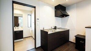 Una cocina moderna con encimera de madera oscura, campana extractora negra y pileta blanca.