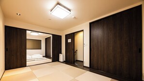 Una habitación con suelo de tatami, puertas de madera oscura y una lámpara en el techo.