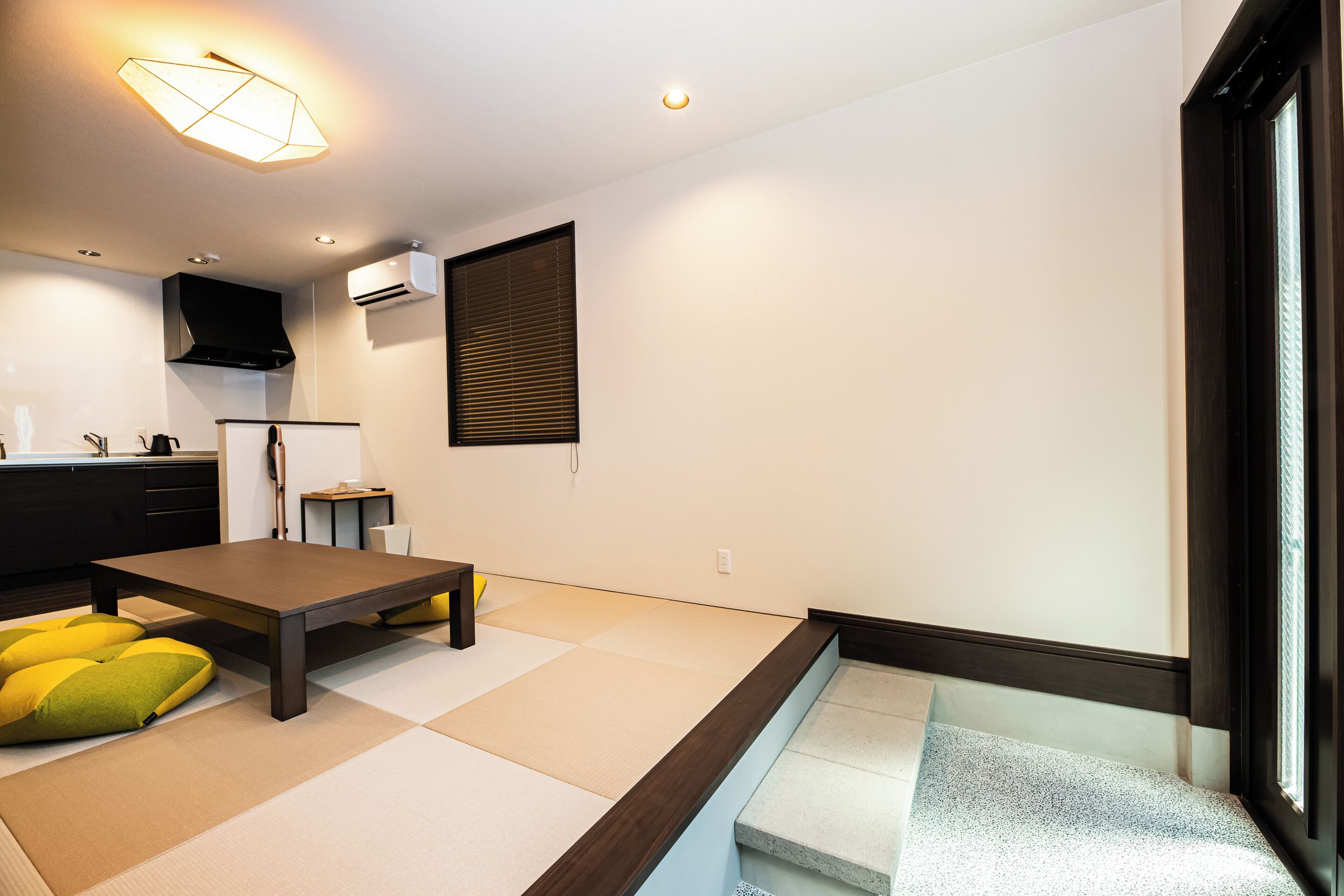 A modern room with tatami flooring, a low table, and a sofa with cushions.