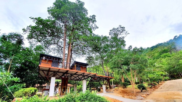 A two-story building with a wooden deck and a staircase leading to the upper floor. - Mountain Front Hut For 2 Rare Birds, Bikes, Nature (Kaeng Krachan)