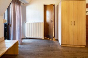 A room with a wooden wardrobe, a radiator, and a bench.