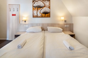 Habitación de hotel con dos camas, un cuadro en la pared y dos lámparas de pared.