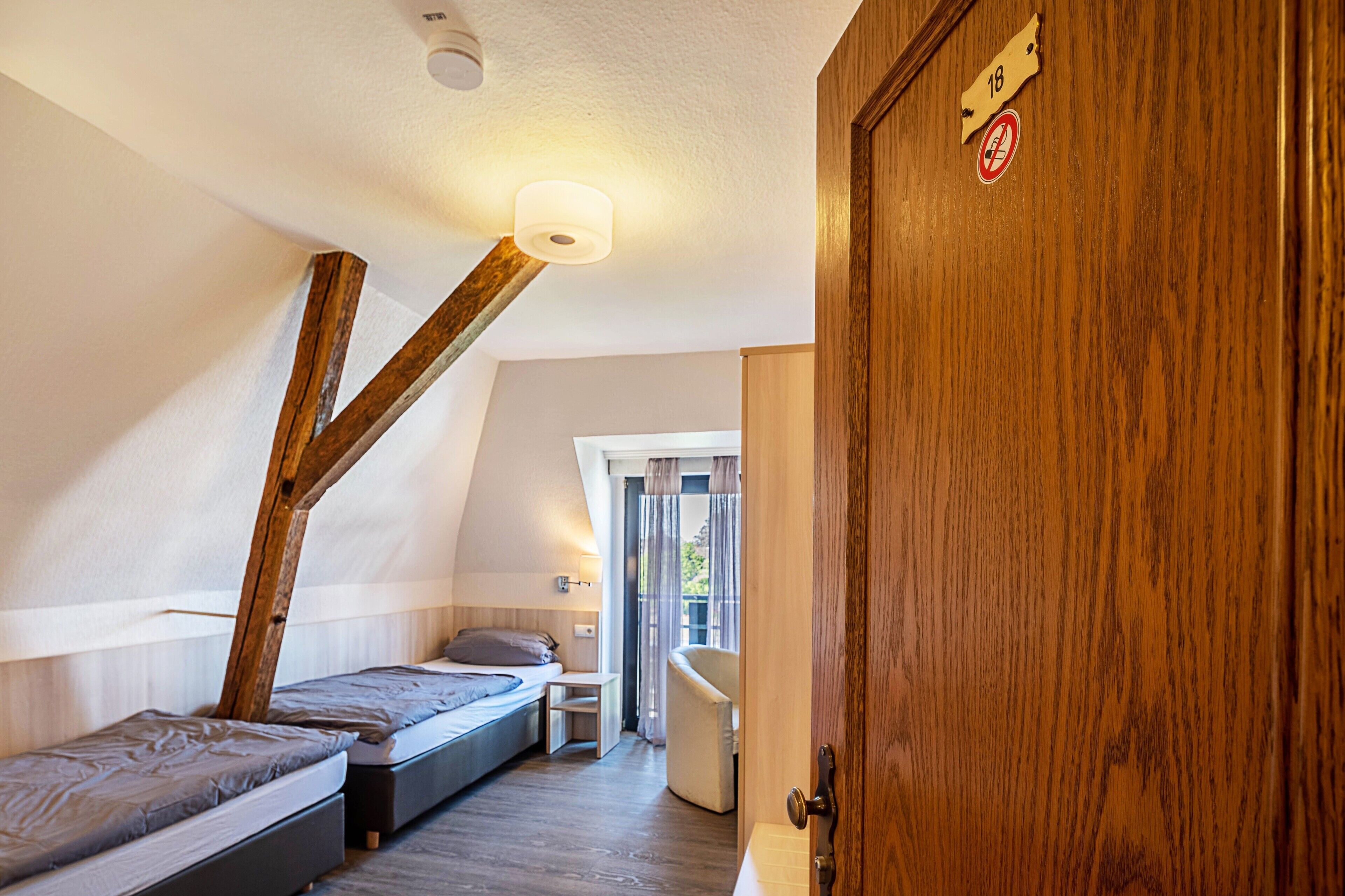 A bedroom with a loft bed, a bedside table, a chair, and a view of the outdoors.