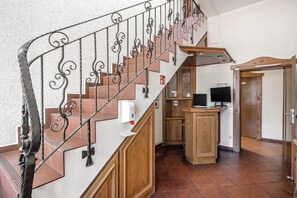 A staircase with a wrought iron railing, wooden steps, and a hand sanitizer dispenser.