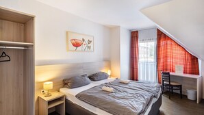 A bedroom with a bed, bedside tables, a desk, and a chair.
