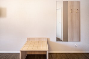 Une pièce avec un banc en bois, un miroir et une armoire.