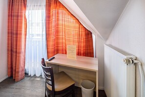 Une petite pièce avec un bureau, une chaise et un radiateur.