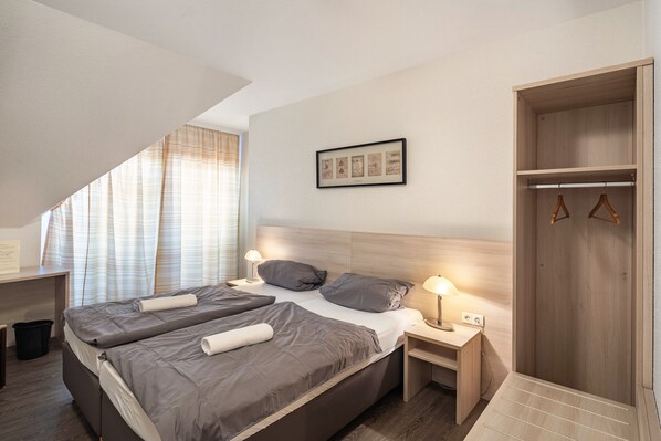 Ein Schlafzimmer mit einem Bett, Nachttischen, einem Kleiderschrank und einem Fenster mit Vorhängen.