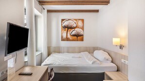 Habitación de hotel con cama, escritorio con computadora, televisión y un cuadro en la pared.