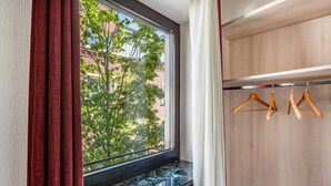 A room with a window, a radiator, and a wooden wardrobe with hangers.