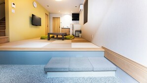 A modern interior with a staircase, a flat-screen TV, a kitchen area, and a dining space. - Irodori Hotel KOU (fukuokashi,hakataku,taihakumachi)