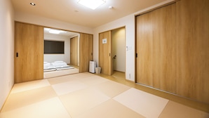 A room with tatami flooring, wooden sliding doors, a bed with white bedding, a bedside table, and a bedside lamp. - Irodori Hotel KOU (fukuokashi,hakataku,taihakumachi)