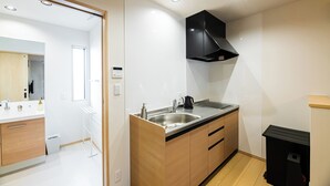 A modern kitchen with a stainless steel sink, wooden cabinets, and a black range hood. - Irodori Hotel KOU (fukuokashi,hakataku,taihakumachi)