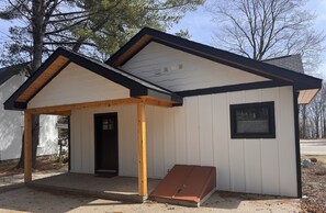 A small, single-story building with a covered porch, a door, and a window.