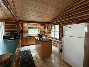 Une cuisine de style rustique, avec des murs en bois, un îlot central, un réfrigérateur et un four à micro-ondes.