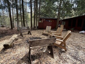 Un chalet rustique avec un foyer et des chaises en bois, situé dans un cadre forestier.