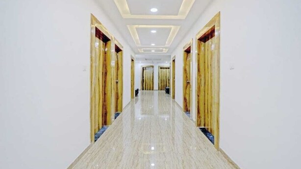 A hallway with a polished marble floor, wooden doors, and recessed lighting.