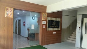 A hotel reception area with a reception desk, a clock, and a staircase leading to another floor.