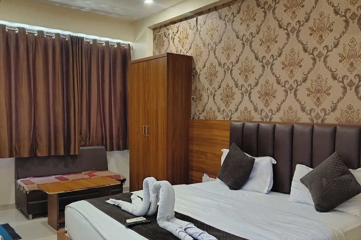 Habitación de hotel con una cama grande, un armario de madera, una mesita y un ventilador de techo.