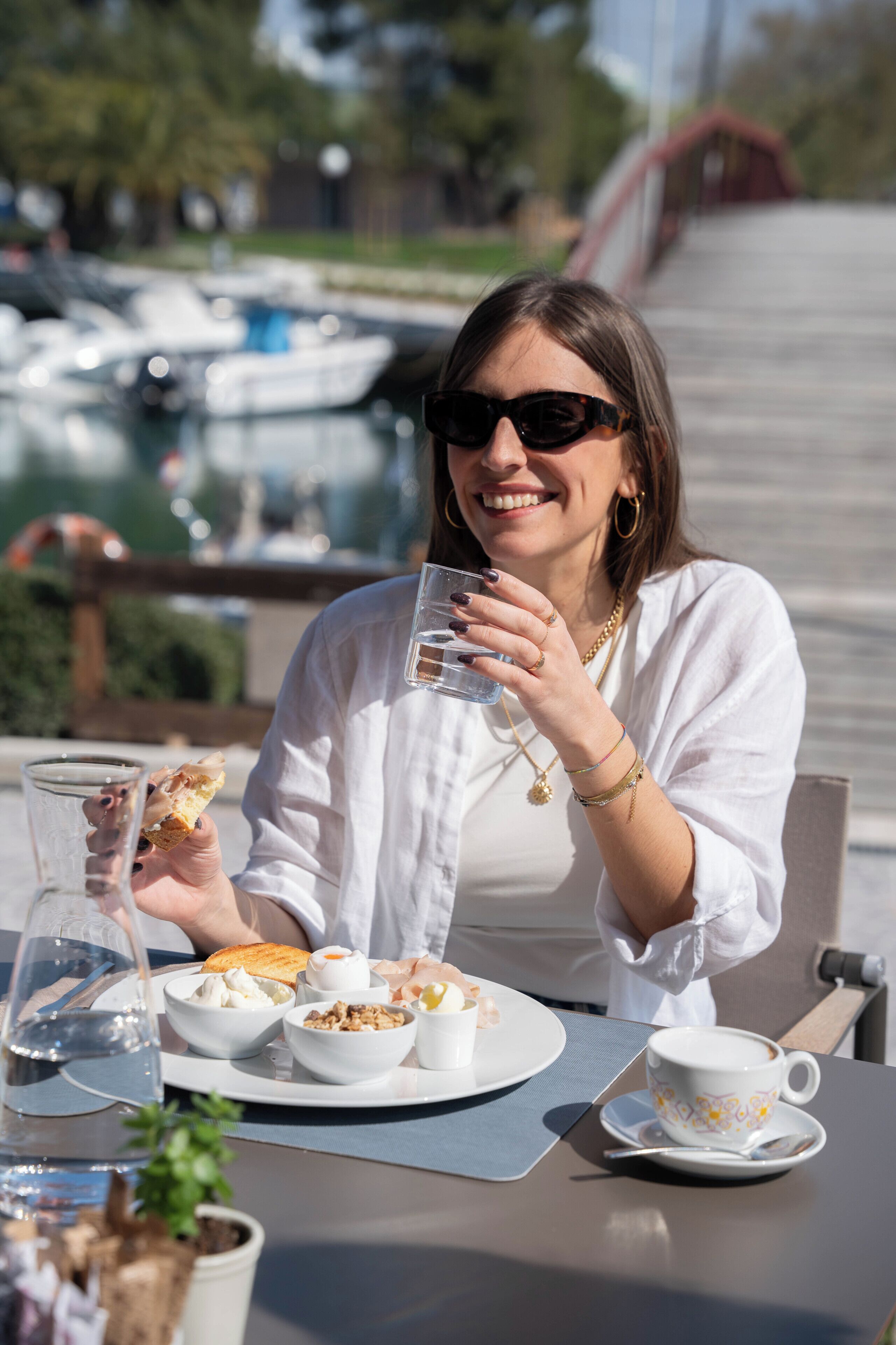 A person seated at a table with a glass of water, a plate with food, and a cup.