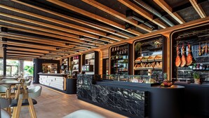 Zona de bar moderna con vigas de madera, encimeras de mármol y asientos.
