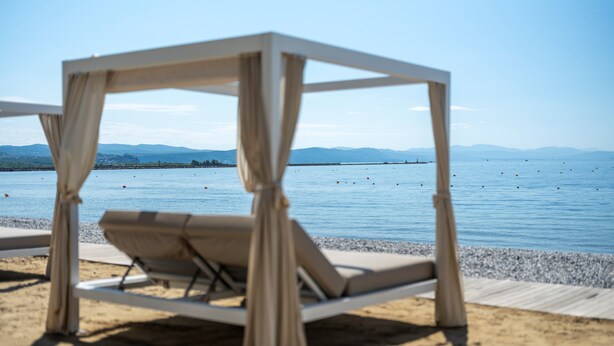 Una silla de playa con vista al mar y montañas a lo lejos.