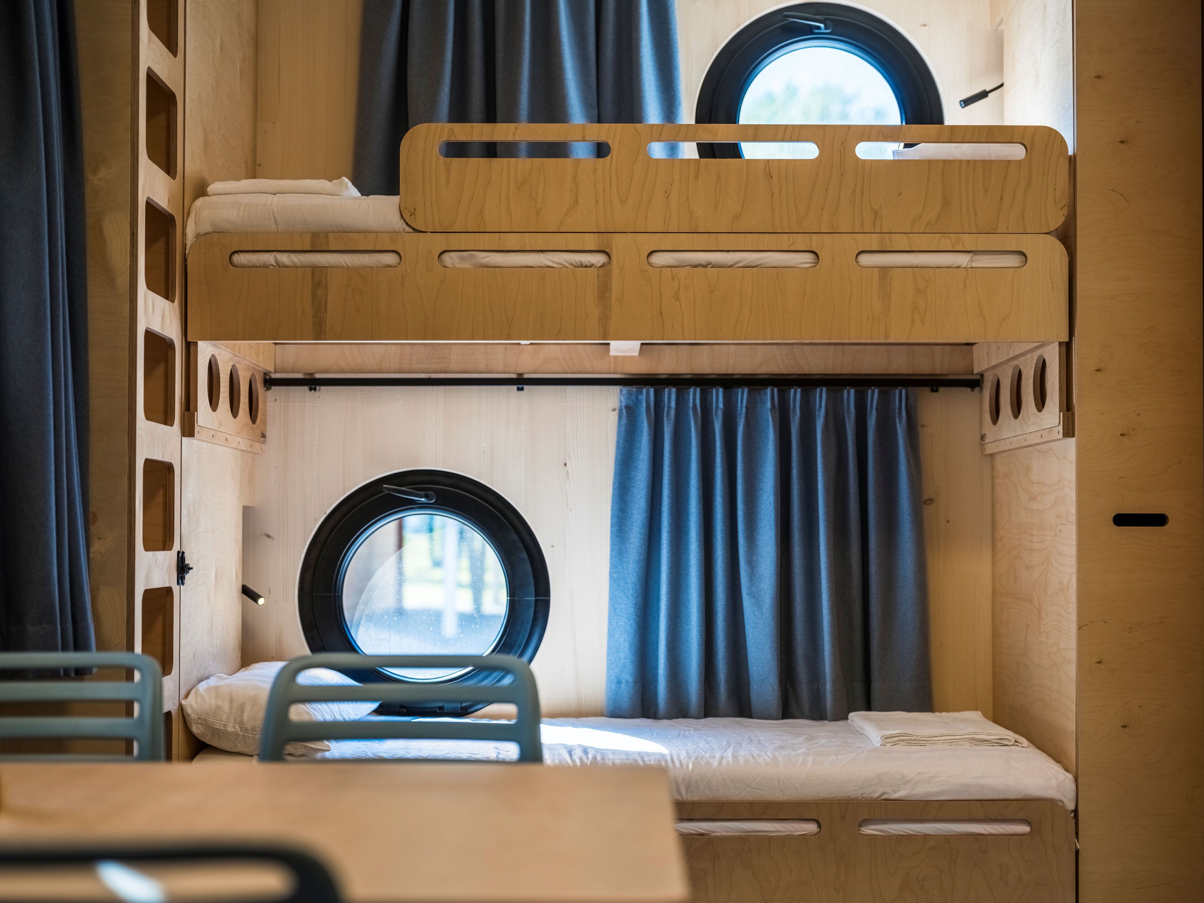 A bunk bed room with a window, curtains, and a table.