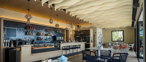 A modern bar area with a counter, shelves with bottles, and a seating area with tables and chairs.