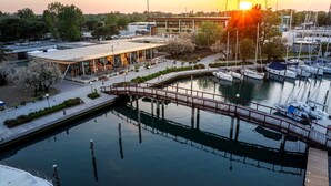 Un puerto deportivo con barcos amarrados, un puente de madera y un edificio con terraza.