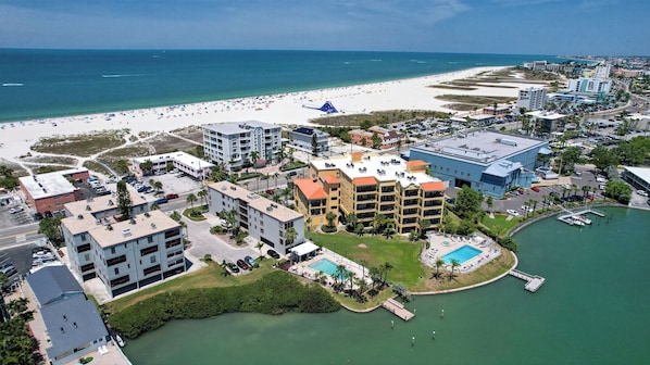 An aerial view of a coastal hotel with multiple buildings, a beach, and a marina. - 2BR 2Ba Treasure Island Luxury waterfront updated Condo., steps to beach access (Treasure Island)