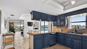 Uma cozinha moderna com armários azul escuro, uma ilha central e vista para o exterior.
