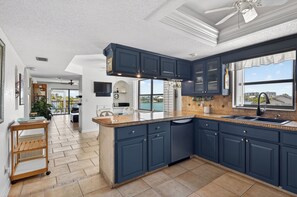 A modern kitchen with dark blue cabinets, a central island, and a view of the outdoors. - 2BR 2Ba Treasure Island Luxury waterfront updated Condo., steps to beach access (Treasure Island)