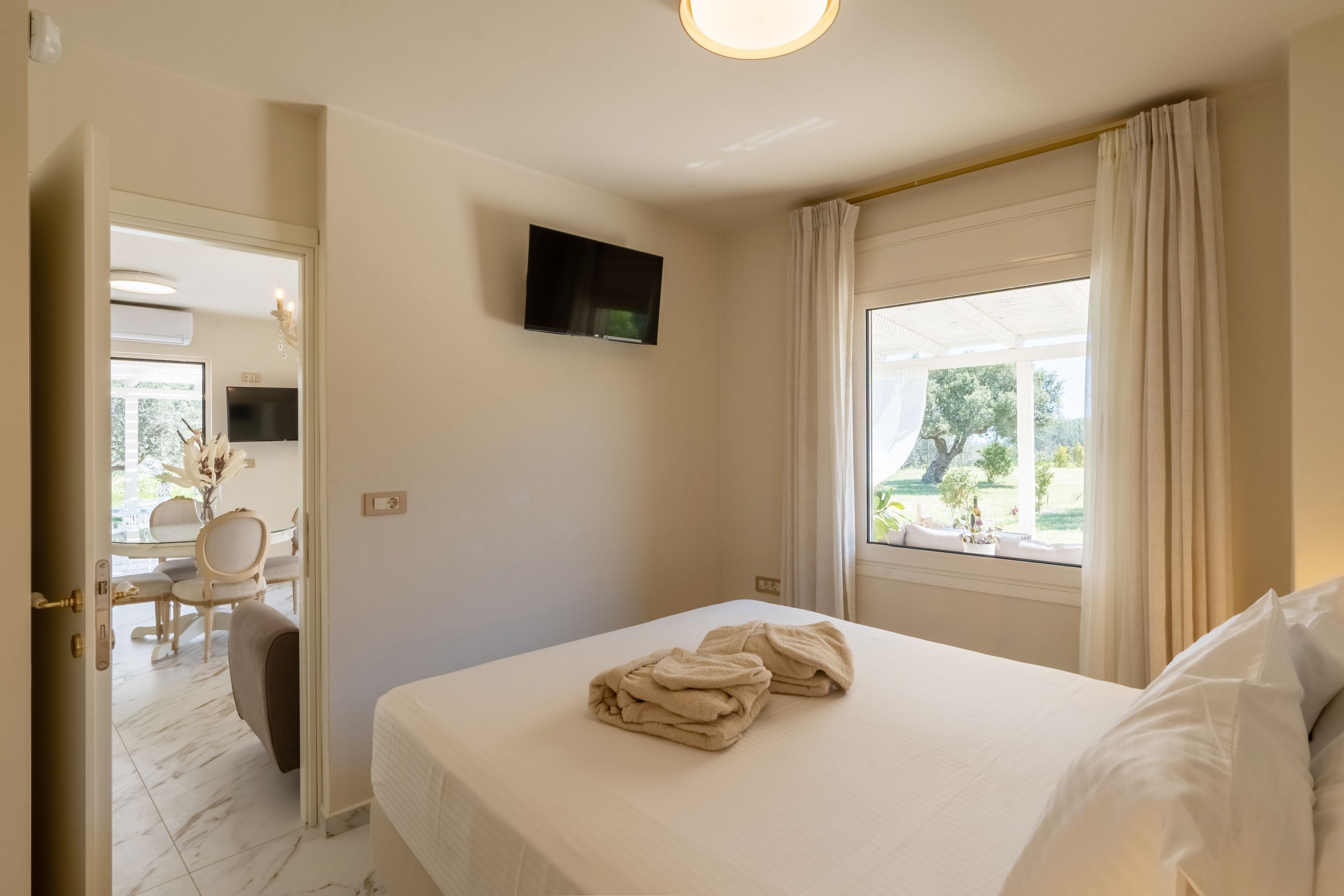 Une chambre d’hôtel avec un lit, un téléviseur fixé au mur, une fenêtre avec des rideaux et une vue sur l’extérieur.
