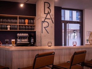 A bar area with a concrete pillar, shelves of wine glasses, a coffee machine, and seating. - Ibis Styles Paris Pont D'Ivry (Ivry-sur-Seine)