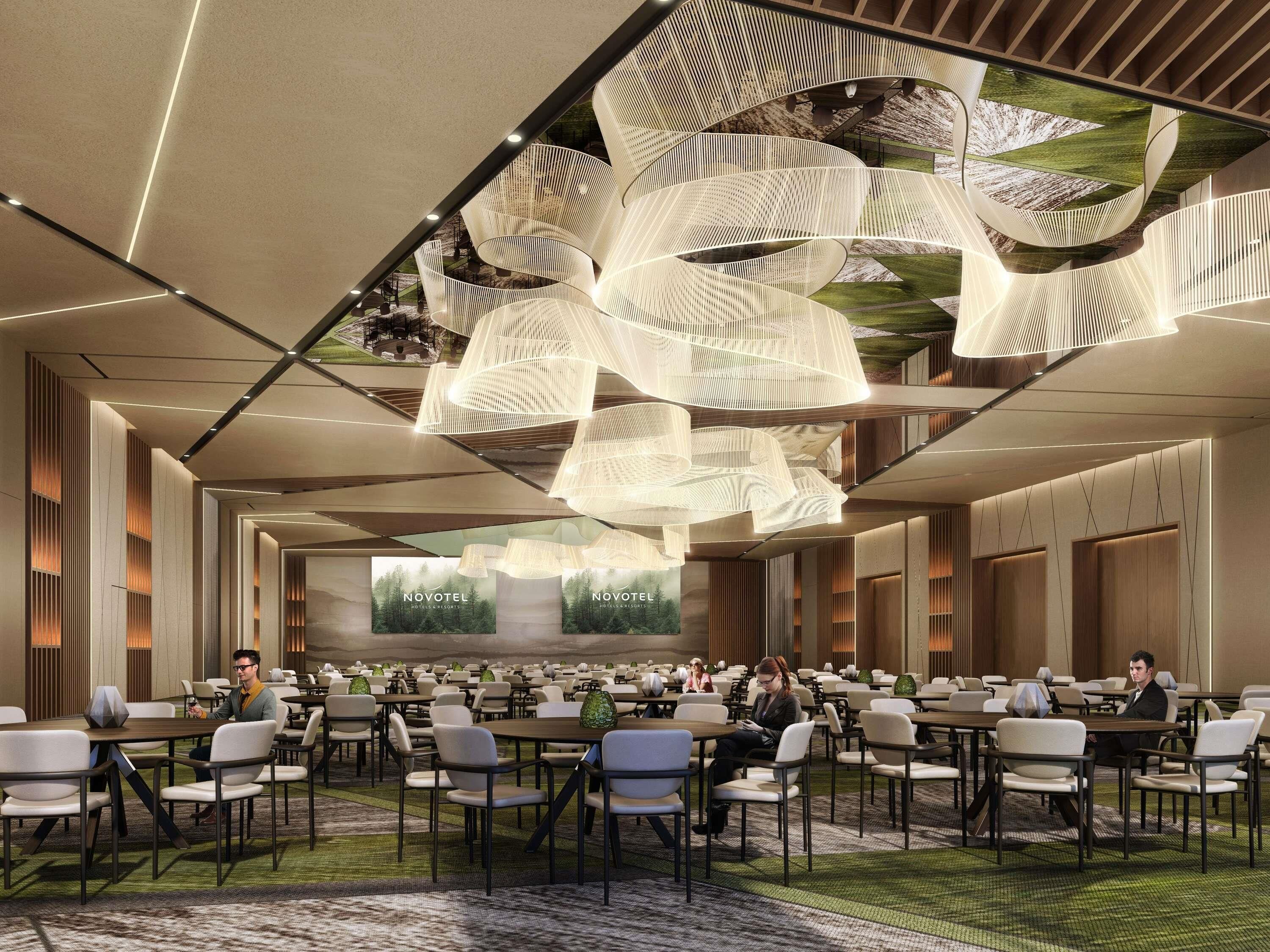 Una hall d'hotel moderna con un'ampia area salotto, un grande schermo che mostra il nome dell'hotel e un'illuminazione del soffitto particolare.