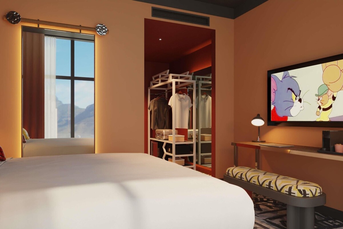 A hotel room with a bed, a closet, a TV, and a window with a view.