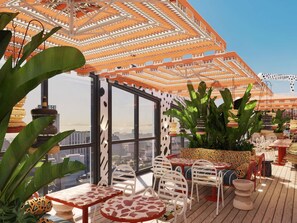 An outdoor terrace with tables and chairs, potted plants, and a patterned ceiling. - Mama Shelter Cape Town (CAPE TOWN)