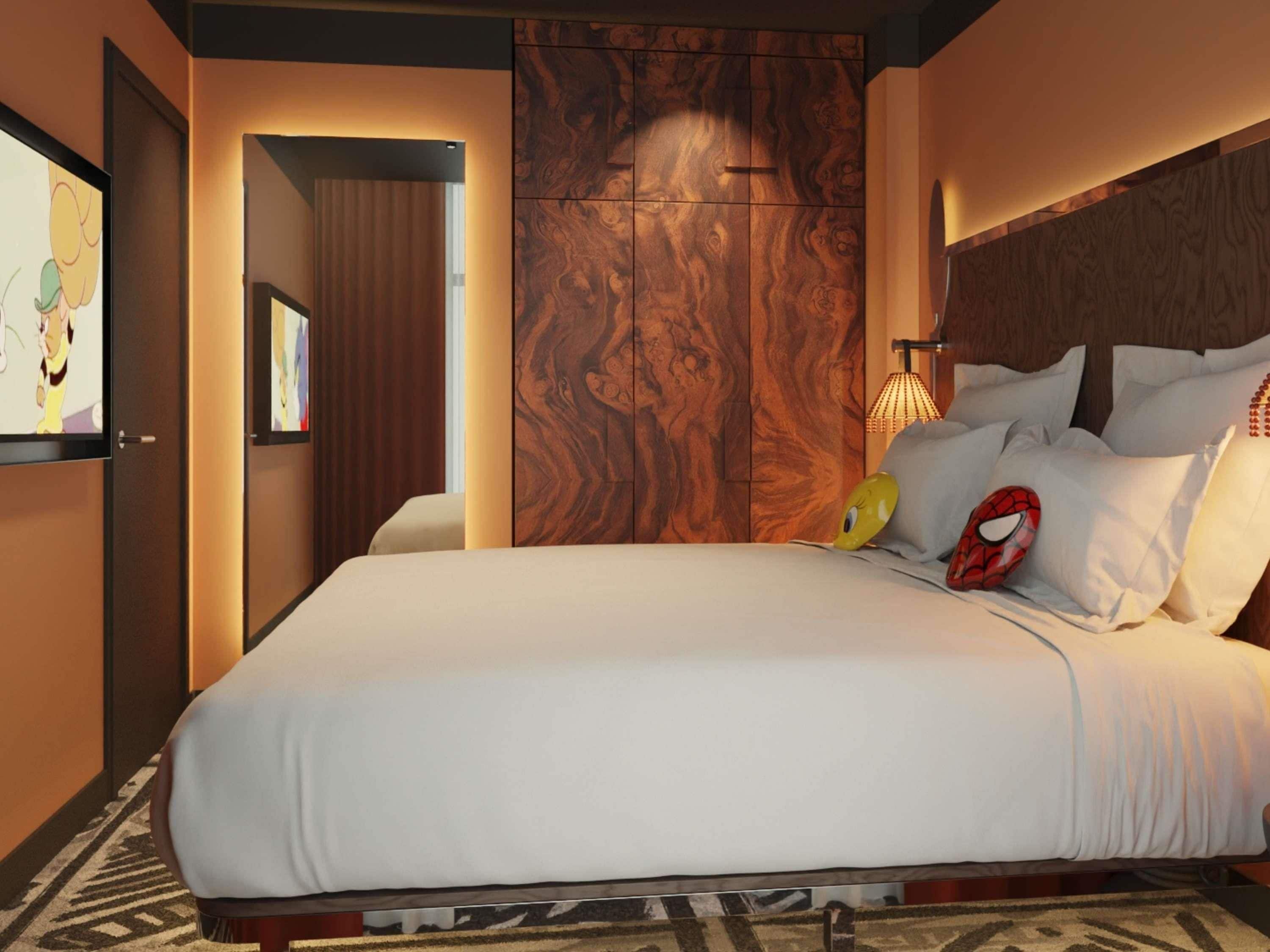 Een hotelkamer met een groot bed, een houten hoofdeinde en een aan de muur bevestigde televisie.