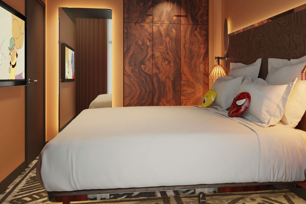 A hotel room with a large bed, a wooden headboard, and a wall-mounted TV.