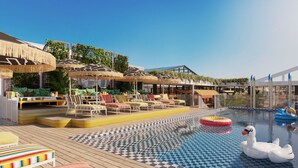 A poolside area with lounge chairs, umbrellas, and a swan float. - Mama Shelter Cape Town (CAPE TOWN)