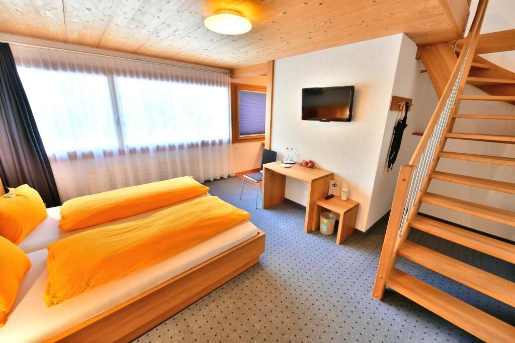 A room with a bed, a desk, a TV, and a staircase.