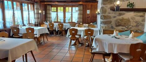 Een restaurant met houten wanden, stenen accenten en meerdere tafels met stoelen.
