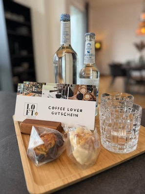 Ein Tablett mit einem Geschenkset für Kaffeeliebhaber, bestehend aus einer Flasche, Gläsern und Snacks.
