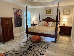 Un lit à baldaquin, un tapis à motifs zébrés, des tables de chevet en bois et un tableau accroché au mur.