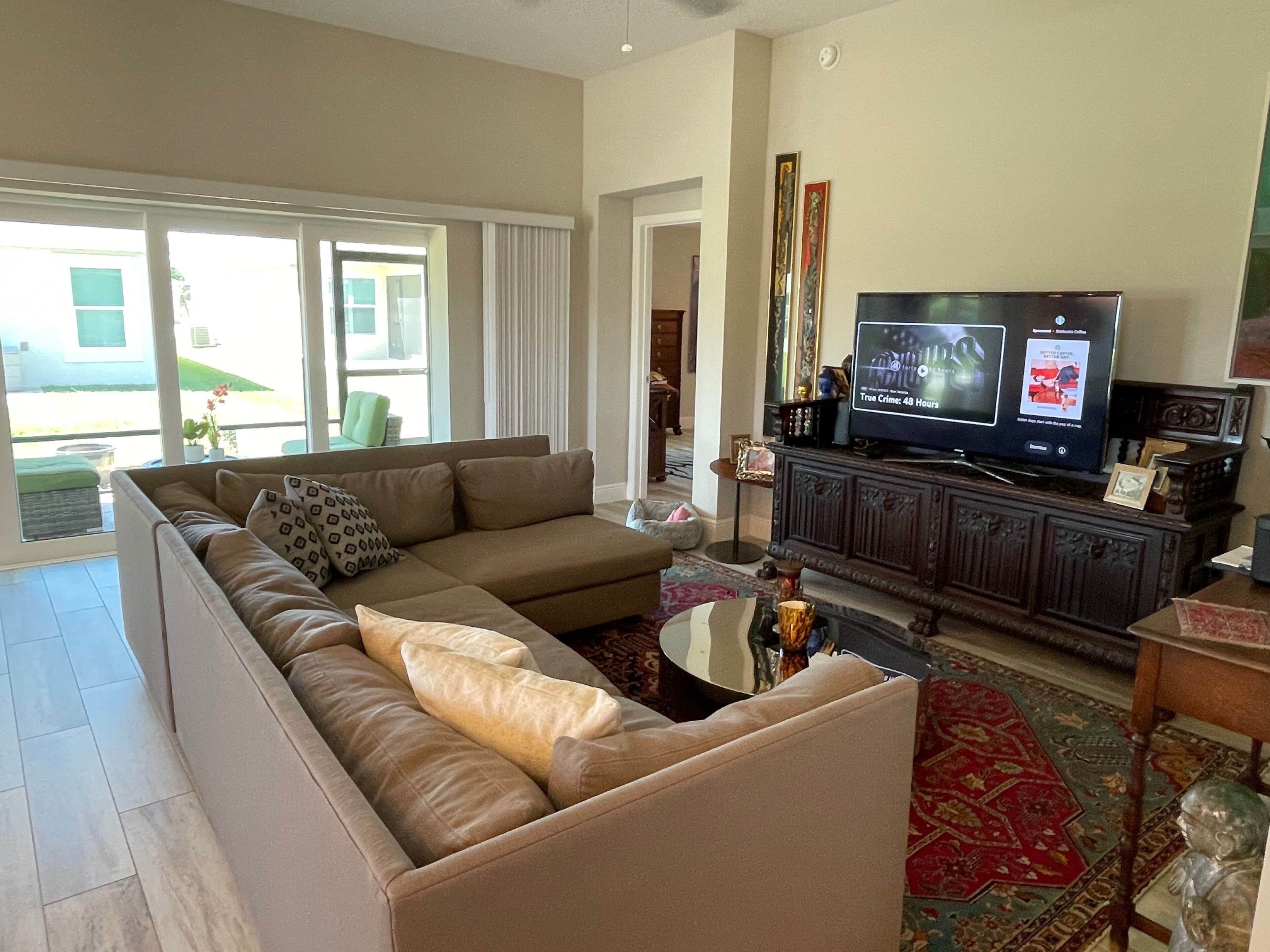 Una sala de estar con un sofá modular, un televisor de pantalla plana, una mesa de centro y una alfombra estampada.